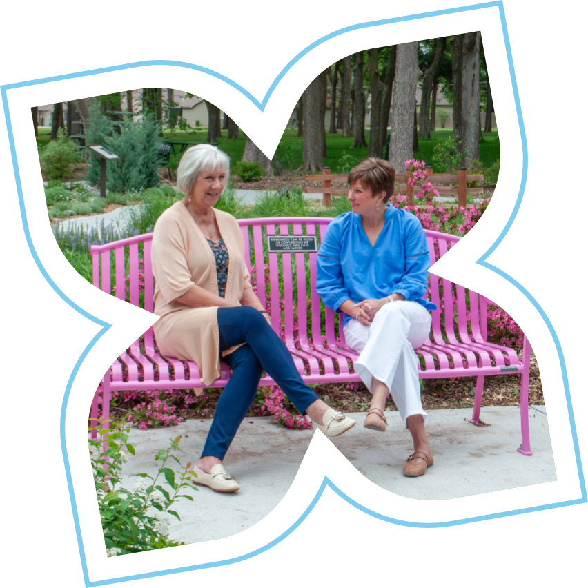 Two women in conversation on a bench in a community garden